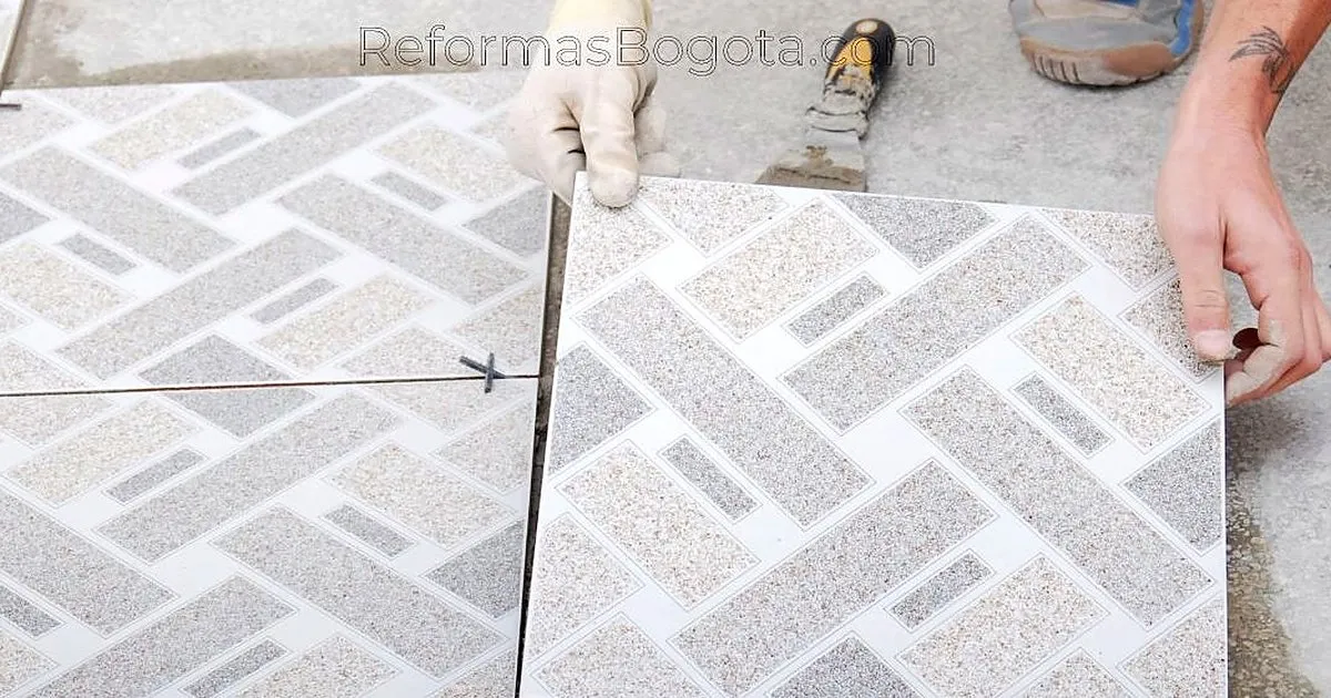 Dos instaladores colocando una baldosa de porcelanato con diseño gris junto a piezas ya pegadas con crucetas