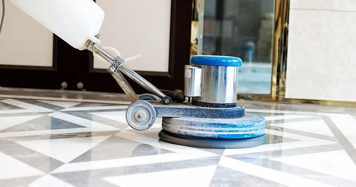 Máquina pulidora con tanque de agua trabajando sobre un piso de mármol blanco y gris con diseño geométrico