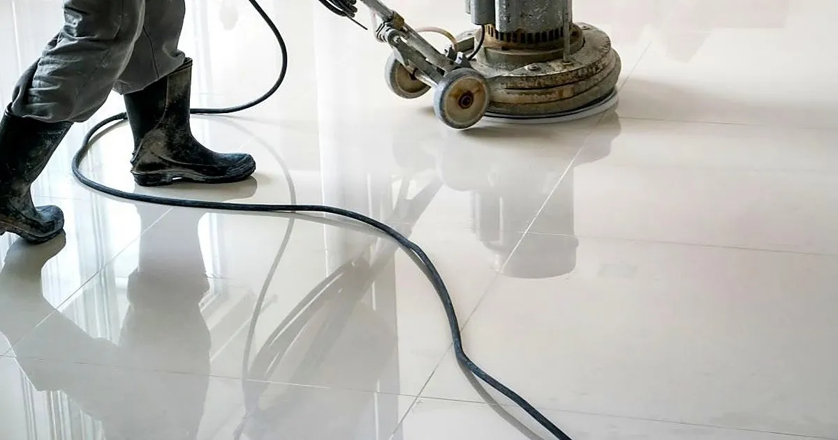 Operario con botas pasando una máquina rotativa sobre un piso de porcelanato blanco brillante que refleja la luz