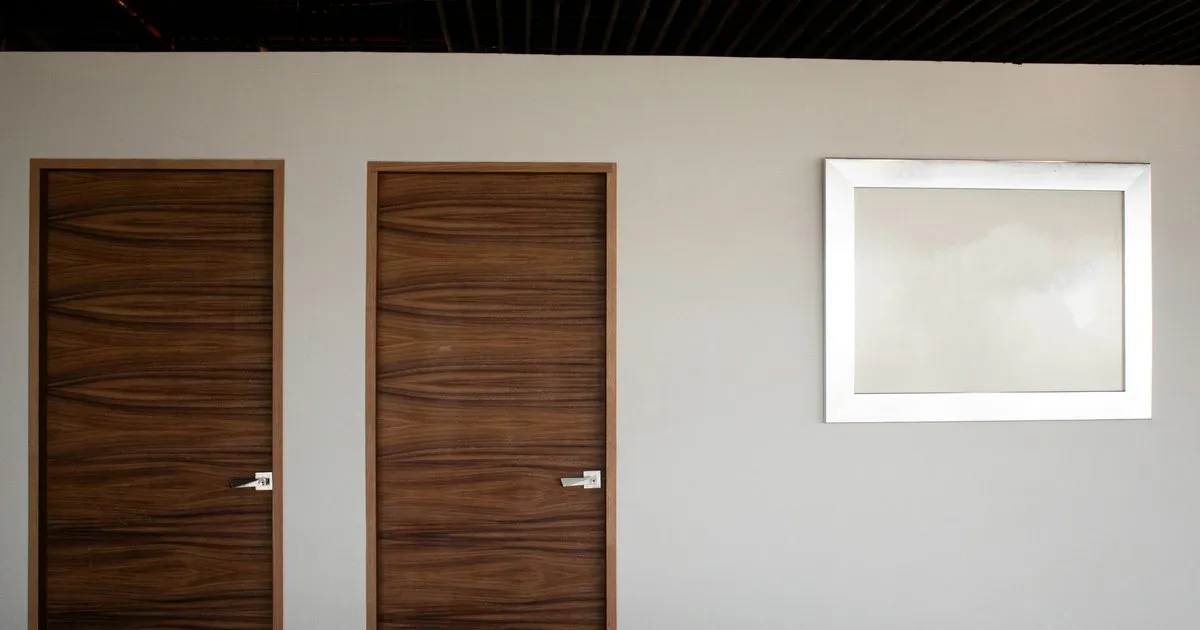 Dos puertas de madera con veta horizontal oscura y manija metálica instaladas en un muro claro