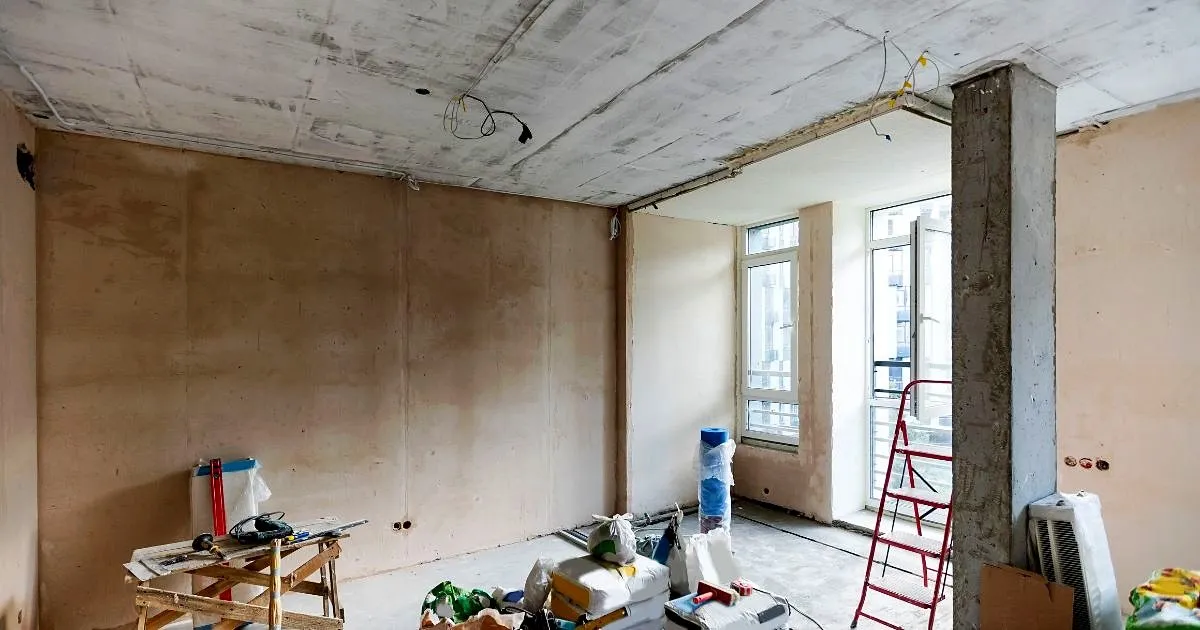 Interior de apartamento en obra gris con muros pañetados, columna de concreto, cableado a la vista y materiales listos para los acabados
